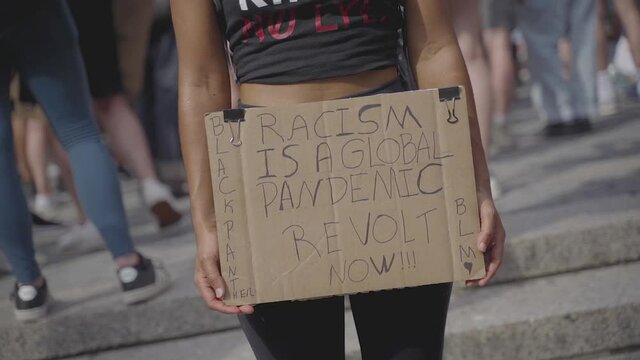 Racism is Global Pandemic Sign in Hands of a Young Female on Black Lives Matter Protest in New York USA, Close Up Slow Motion Detail