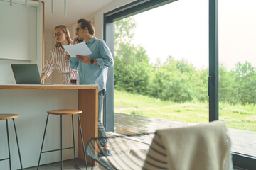 Obraz premium View from afar of family couple of business on the kitchen with laptop