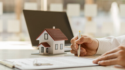 Real estate brokerage contracts for sale and rent with a house on the table in the office.
