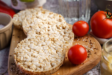 Crispy puffed rice cakes on table hummus spread and tomato vegetables and sesame seeds on the table - close up view on healthy vegetarian or vegan breakfast gluten free