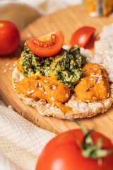 Crispy puffed rice cakes on table with hummus spread spinach with eggs and tomato and vegetables on the table - top view on healthy vegetarian breakfast gluten free