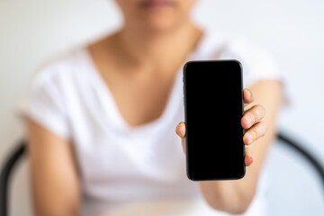 Closeup of woman hand holding and show blank isolated black screen mobile smartphone.