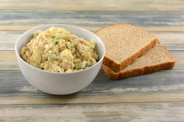 Albacore tuna salad with chopped apple and avocado in white bowl next to two whole wheat bead slices