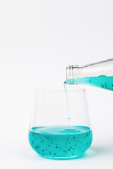 Filling a glass with an exotic cocktail with basil seeds on a light background.