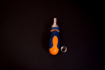 Closeup shot of a blue and orange screwdriver with an adapter isolated on black background