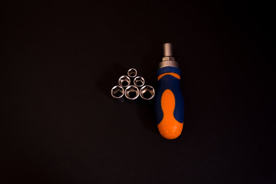 Closeup shot of a blue and orange screwdriver with adapters isolated on black background