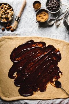 Chocolate spread on the dough and ingredients arranged on the table cloth pictured from above