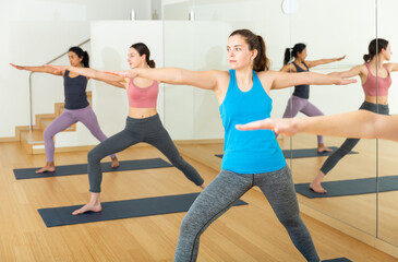 Obraz premium Group of young active females performing yoga in fitness studio