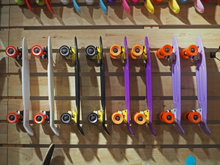 Many surfskate hanging on the skateboard shop wall. Many vibrant color.