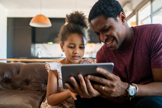 Father and daughter using digital tablet at home. - Powered by Adobe