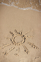 Shape of sun on sand at beach and incoming sea wave. Summer, vacation time and tourism