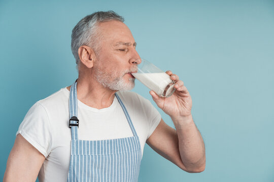 Side View, Senior Man Drinking Milk, Closing His Eyes. Isolated On Blue Background, Copy Space, Place For Text.