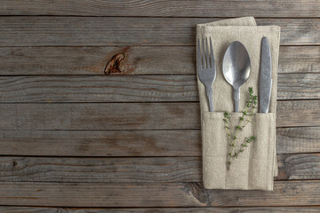 Rustic table setting in natural warm colors. Plate and cutlery with linen napkin over wooden...