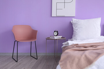 Modern bedside table and chair in interior of bedroom