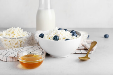 Bowl of cottage cheese with blueberries on light background