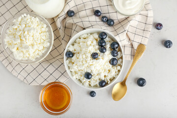 Bowl of cottage cheese with blueberries on light background