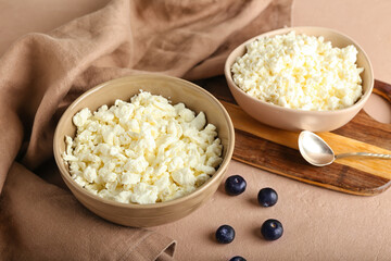 Bowls of cottage cheese on color background