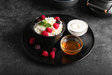 Bowl of cottage cheese with berries on dark background