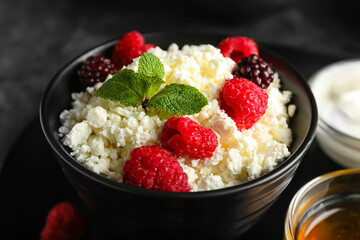Bowl of cottage cheese with raspberries on dark background