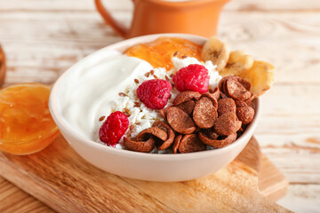 Bowl of cottage cheese with cereal, jam and raspberries on light wooden background