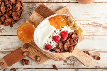 Bowl of cottage cheese with cereal and raspberries on light wooden background