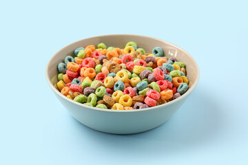Bowl with cereal rings on color background