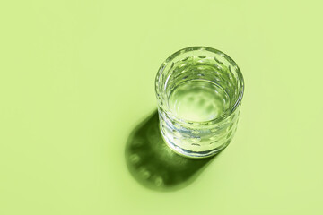 Glass of water on color background