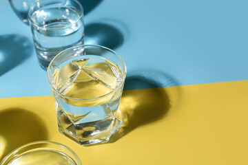 Glasses of water on color background