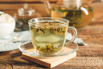 Cup of hot green tea on wooden background