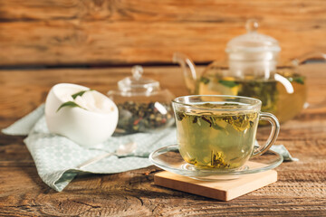 Cup of hot green tea on wooden background