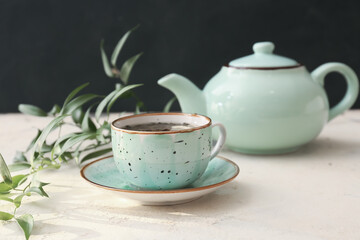 Teapot and cup of hot green tea on table
