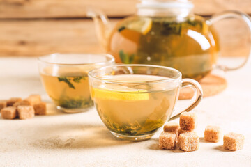 Teapot and cups of hot green tea on table