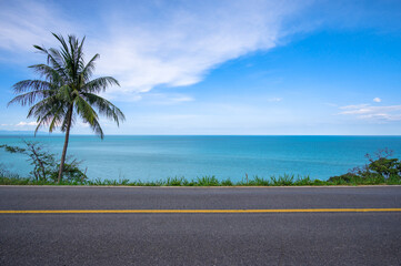 Coconut palm tree on side of asphalt road and tropical seascape scenery in the background. - 428082072
