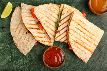 Tasty vegetarian quesadillas, lime and sauces on color background
