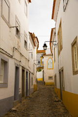 Fototapeta na wymiar View of narrow street with paving stone and old stone houses of Evora, Portugal