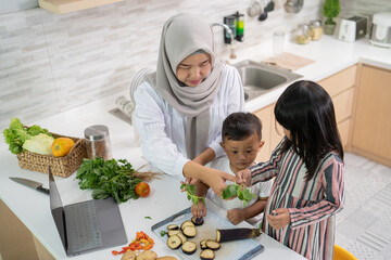 lovely asian woman with daughter and son cooking dinner during ramadan for iftar breaking the fast