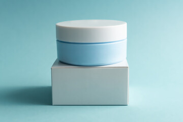 Face cream jar with plastic cap and whire carton box, package on blue background. Mockup unbranded cosmetology product