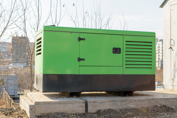 Diesel electric generator on a frame under the hood. Concrete foundation. The background is urban. The concept of an autonomous power plant.