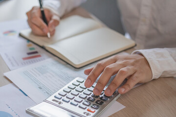 Hand of stress asian young businessman,male is pressing a calculator to calculate tax income and expenses, bills, credit card for payment or payday at home, office.Financial, finance concept.