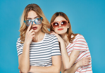 Two women fashionable clothes dark glasses communication friendship cropped view blue background