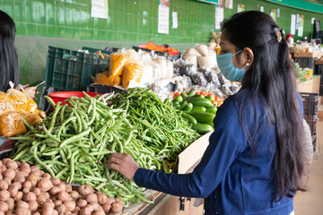 Young indian woman wearing mask buy vegetables from super market during second wave of Coronavirus,...