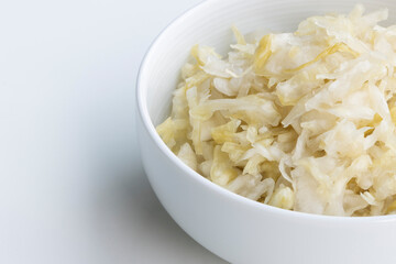 Close up of fresh homemade sauerkraut in a bowl isolated on a white background with copy space. Sauerkraut is finely cut raw cabbage that has been fermented by various lactic acid bacteria.