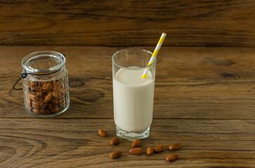 Almond milk in glass with almonds on wooden table