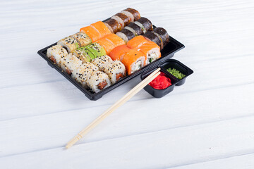 Sushi with chopsticks. Sushi in plastic box. Japan sushi.