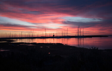 Fototapeta na wymiar Silhouetted sailboats on orange color seascape over sunset sky. 