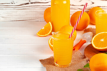 Glass of orange juice and cut oranges on table