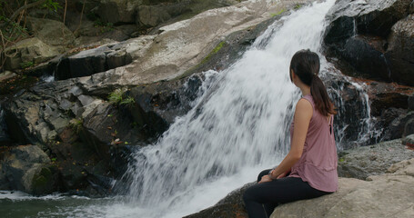 Sport woman sit beside waterfall