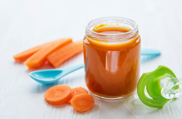 Baby carrot mashed with spoon in glass jar