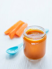 Baby carrot mashed with spoon in glass jar