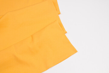 Yellow fabrics folded top view on a white background. Yellow textile	